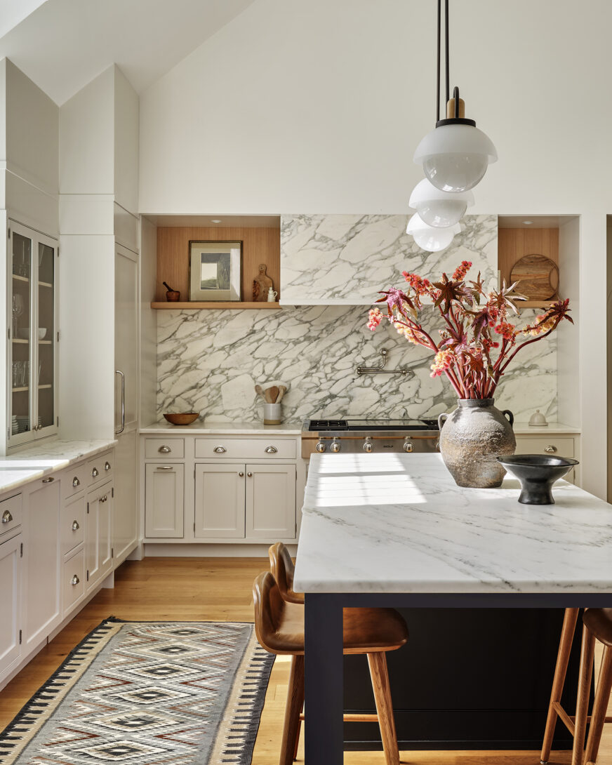 A beautifully designed kitchen that blends classic elegance with modern functionality. Featuring marble countertops and backsplash, warm wood accents, and sleek lighting, this inviting space is perfect for both cooking and gathering.